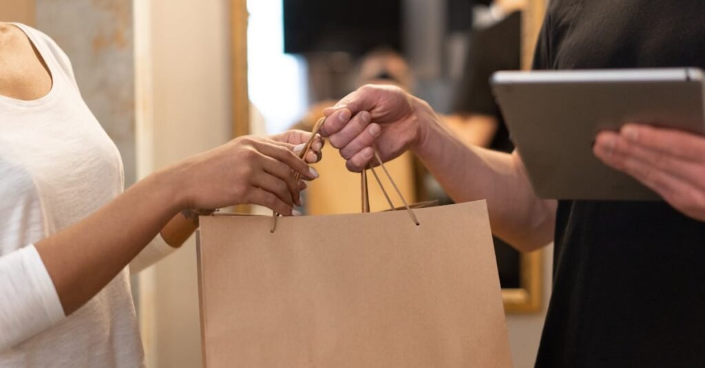 Close-up of hands exchanging a shopping bag indoors, symbolizing modern retail and technology.
